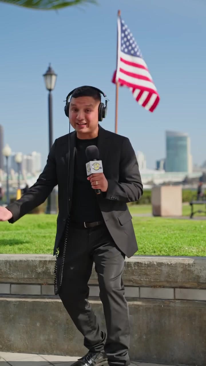The DJ in headphones holding a branded microphone on the San Diego waterfront
