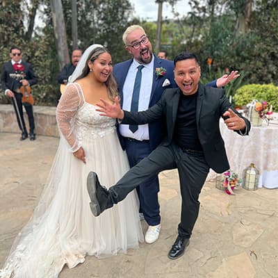 The DJ high-kicking with the bride and guests on a patio