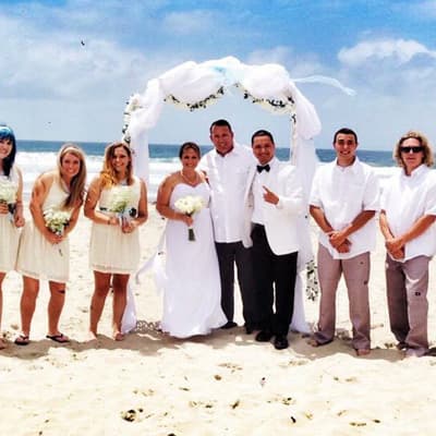 Beach wedding party under a white floral arch